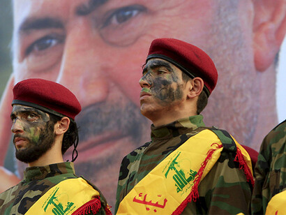 Lebanese Hezbollah members stand in front of a picture of one of Hezbollah's top commanders who was killed fighting in Syria, during his funeral in al-Luwaizeh, southern Lebanon
