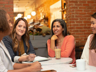 Two women working together in a business meeting at a café, discussing ideas and collaborating in a relaxed setting