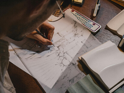 A creative architecture student viewed from above, sketching an architectural design in an imaginative workspace