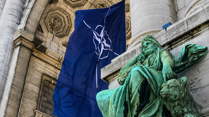 NATO flag displayed beneath the historic arcades of the Cinquantenaire in Brussels, Belgium