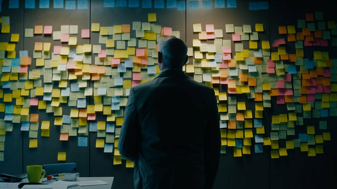 A man staring at a board filled with colorful adhesive notes after a brainstorming session