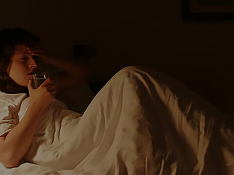 A woman, shaken by a recent nightmare, lies in bed, feeling scared and vulnerable