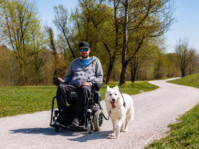 A service dog accompanies a man with a disability as they relax together in a quiet public park