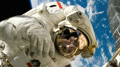 An American astronaut working outside the International Space Station, highlighting the exterior structure and the presence of ISS astronauts in orbit