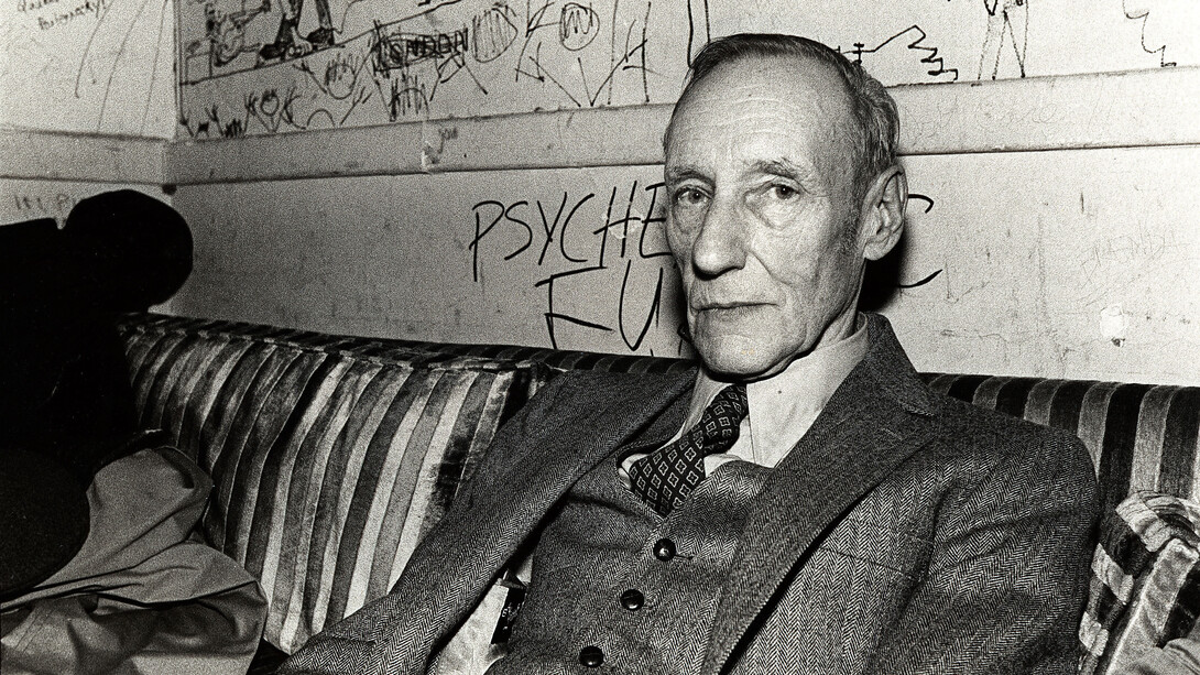 The writer, William Burroughs, at a dive bar dressed in a three-piece suit