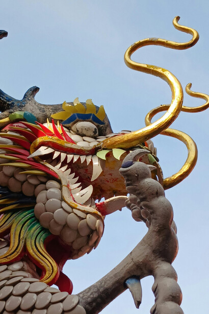 A vibrant dragon statue in Thailand stands against a clear sky, reflecting the symbolism of Naga serpent mythology