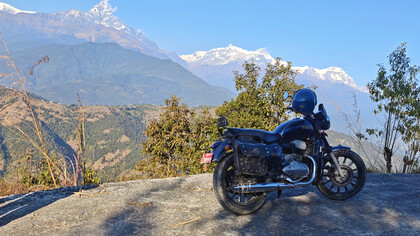 A solitary motorcycle rests quietly before the lush, rolling green mountains of Nepal’s Himalayan landscape