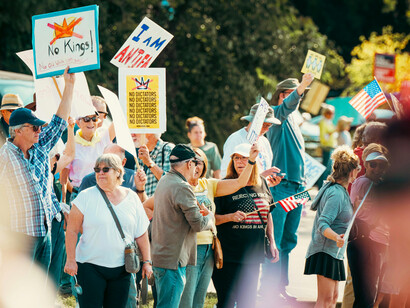 A crowd of demonstrators holds signs and American flags during a peaceful pro-democracy protest in the United States