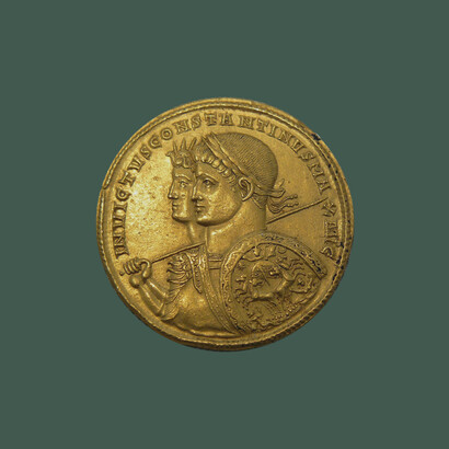 Busti a sinistra di Sol Invinctus con aureola e di Costantino con corona d’alloro e corazza, che regge una lancia sopra la spalla destra e uno scudo ovale sul braccio sinistro con una quadriga del sole al galoppo. Moneta d’oro da nove solidus coniata a Tarragona nel 313 d.C.