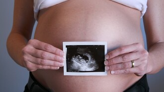 Una embarazada muestra una foto de su feto ante su vientre