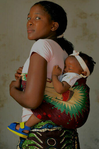 Bebê dorme na capulana nas costas de sua mãe