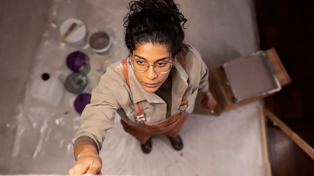 An artist works in their home studio, surrounded by unfinished artwork, capturing the creative process while navigating burnout and inspiration