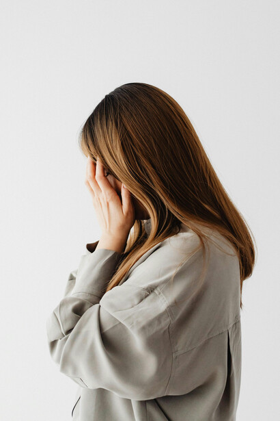 Woman in a gray long-sleeve shirt covering her face — symbolizing resistance to change, inner transformation, and human resilience