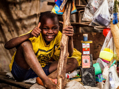With a thumbs up and a smile, the boy embodies hope and resilience amidst the challenges of poverty