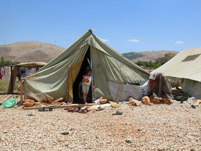 Una niña se asoma desde la tienda de un campamento de refugiados en Líbano