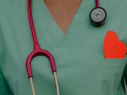 A medical professional in a green uniform wears a stethoscope around their neck