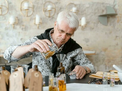 An individual at a table surrounded by assorted fragrances