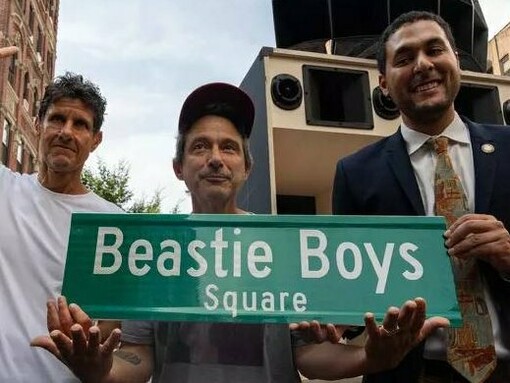 Mike D, Ad-Rock e o vereador Lincoln Restler erguem a placa oficial da 'Beastie Boys Square' durante a cerimônia de inauguração em Nova York