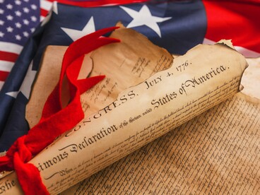 The Declaration of Independence resting beside the American flag, representing the principles on which the nation was founded