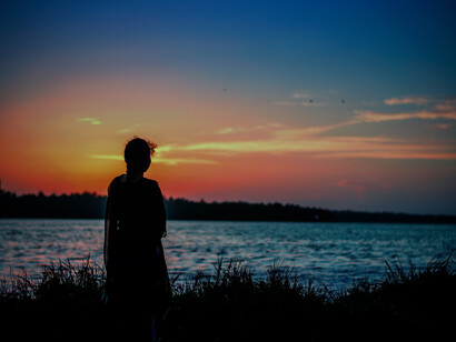 Mujer solitaria contempla la puesta de sol junto a la orilla de un lago
