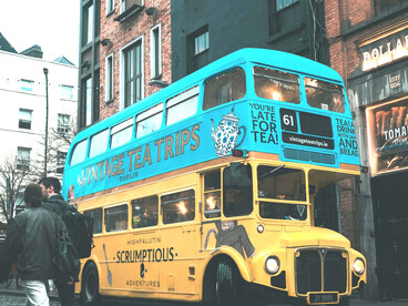 A blue and yellow vintage double-decker bus on a rain-soaked cobblestone street in Dublin, Ireland