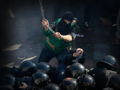 Hombre golpea con una cadena a una tropa de la policía de ucrania en el invierno de 2014 en Kiev, Ucrania