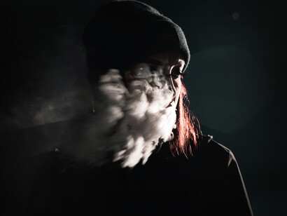 Una mujer exhala humo entre las sombras de la noche