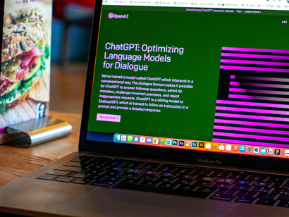 A sleek MacBook is open, with the screen showcasing the homepage of ChatGPT, an AI-driven language model crafted to streamline communication and offer valuable information to users