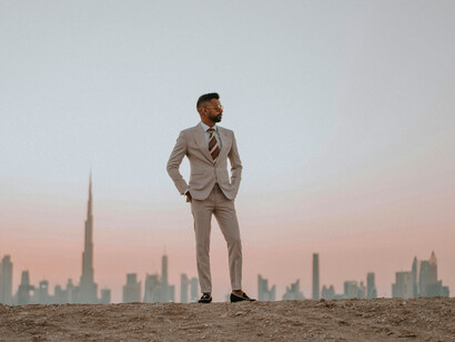 Dubai, United Arab Emirates. A man in a beige suit stands on the sand