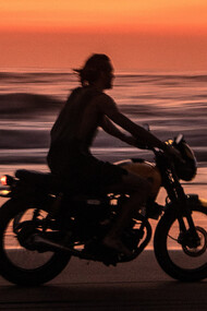 Homem pilota moto em areia da praia próximo ao mar