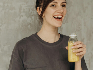 Woman holding a bottle of juice after a gym workout, representing a fitness influencer promoting healthy habits