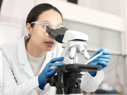 A female scientist places drops of water on the slide under a microscope