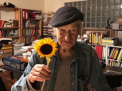 Jonas Mekas presenting a sunflower to the camera