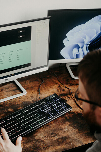 A man seated at a desk, typing code on his computer
