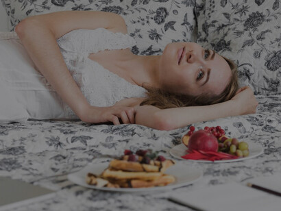 Healthy sleep and diet: A young woman wakes up refreshed, enjoying a nutritious breakfast in bed, illustrating the benefits of proper nutrition on sleep quality