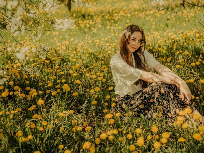 Mulher em campo de flores. A energia, que antes parecia inesgotável, se dissipa mais rápido. Os cansaços chegam mais cedo e as recuperações se tornam mais lentas. A musculatura já não responde com a mesma facilidade, e o metabolismo, fiel companheiro dos anos mais jovens, parece ter se rebelado. Aqueles quilos a mais que antes poderiam ser ignorados começam a se instalar, sem pedir licença, e a relação com a alimentação e com a atividade física se transforma em algo mais desafiador