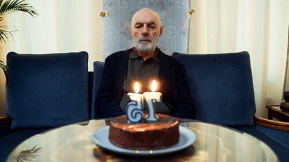 A solitary elderly gentleman, with a hint of nostalgia in his eyes, quietly extinguishes the birthday candles on his cake, marking another year of his life in solitude