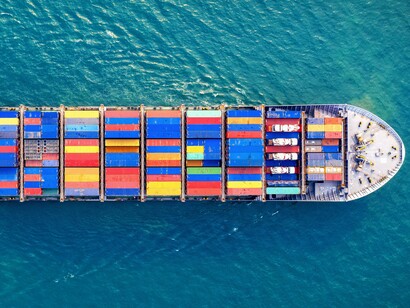 A container ship seen from above amid vast waters, representing the lifelines of global commerce and economic exchange