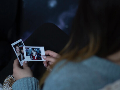 Ragazza guarda malinconica delle vecchie polaroid scattate qualche tempo prima 