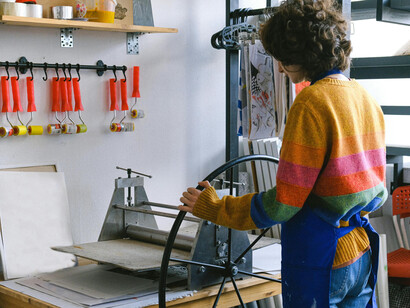A colorfully dressed woman working on a vintage printing press