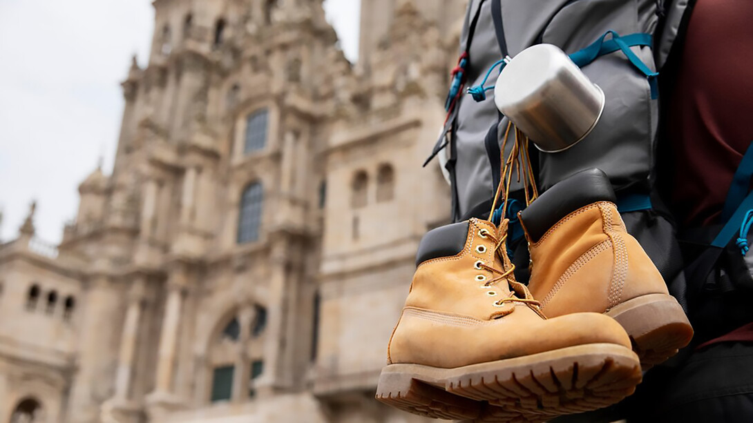 A male traveler with a backpack and dangling shoes exploring a historic cathedral in Europe