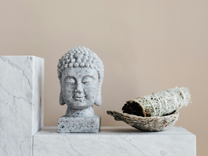 A marble Buddha head next to some incense