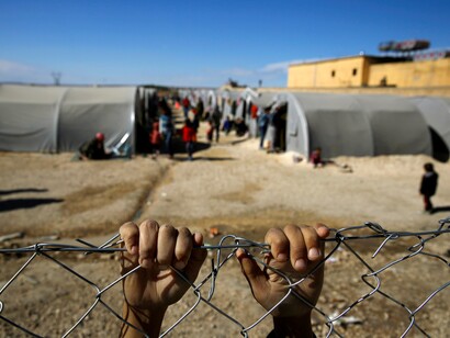 Las manos de un refugiados en la valla de uno de los campamentos en que se alojan