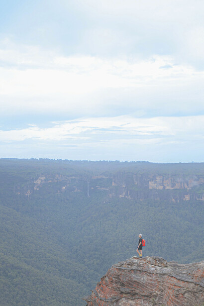 Un chico que llegó a la cima de una montaña, contemplando la inmensidad de su logro