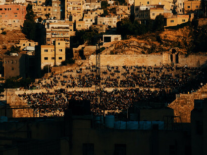 A crowded Roman theatre glowing under the warm light of sunset, where audiences gather to celebrate culture, music, and community