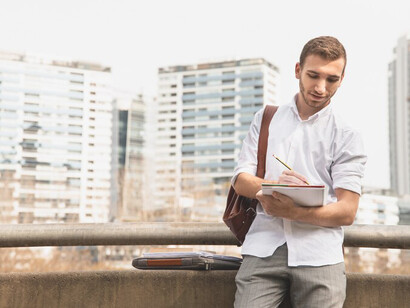 International student in a vibrant city holding study notes, showcasing the challenges of academic migration and student life