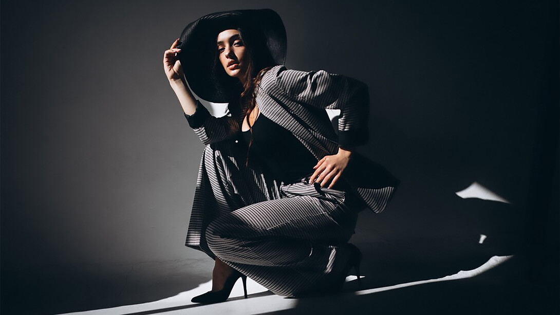 A woman in a business suit, accessorized with a hat