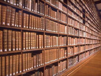 Estantería de una biblioteca llena de libros de papel