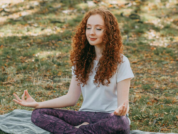 Healthy woman doing yoga outdoors on the grass in a park