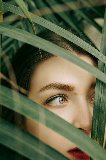 Portrait of a woman’s face partially hidden behind green leaves, symbolizing self-discovery and the search for meaning
